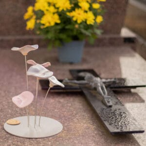 Plaque funéraire personnalisée en inox avec fleurs en céramique claires, installée sur un monument cinéraire